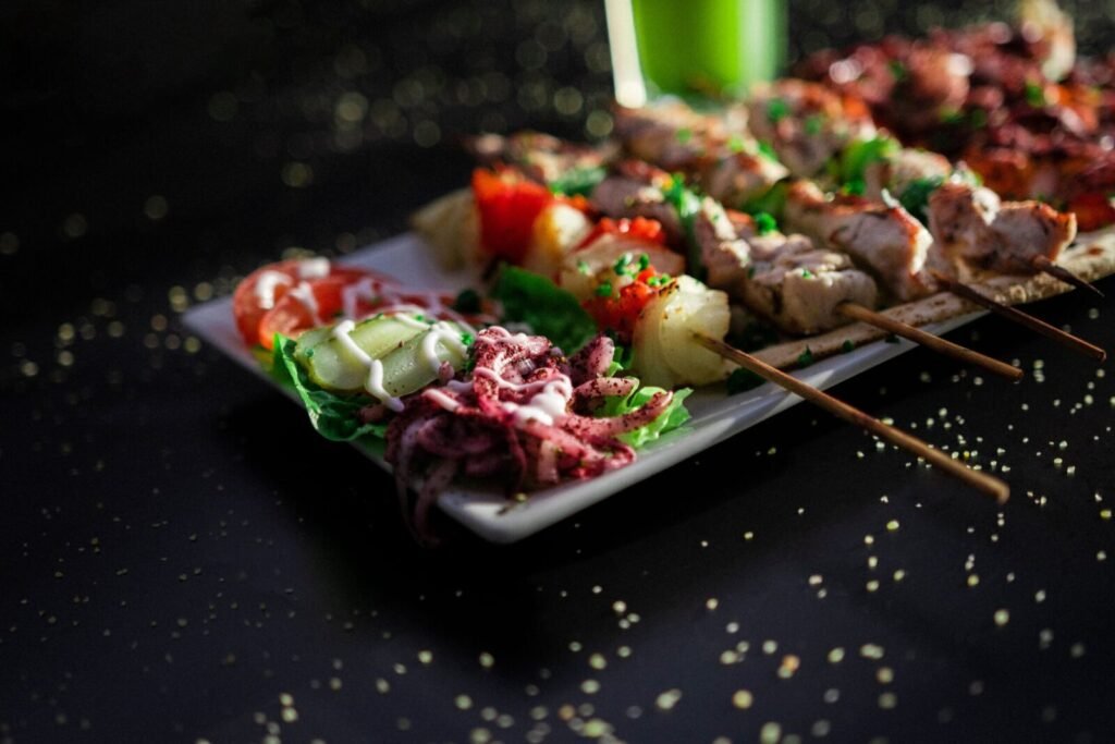 A plate of grilled skewers with vibrant salad and drink, perfect for a summer meal.