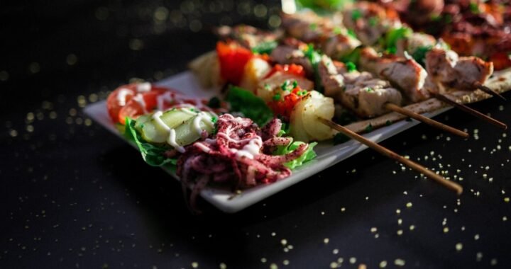 A plate of grilled skewers with vibrant salad and drink, perfect for a summer meal.