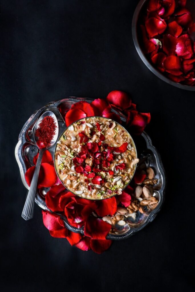 Rich Indian dessert garnished with rose petals and nuts, presented on an elegant platter.