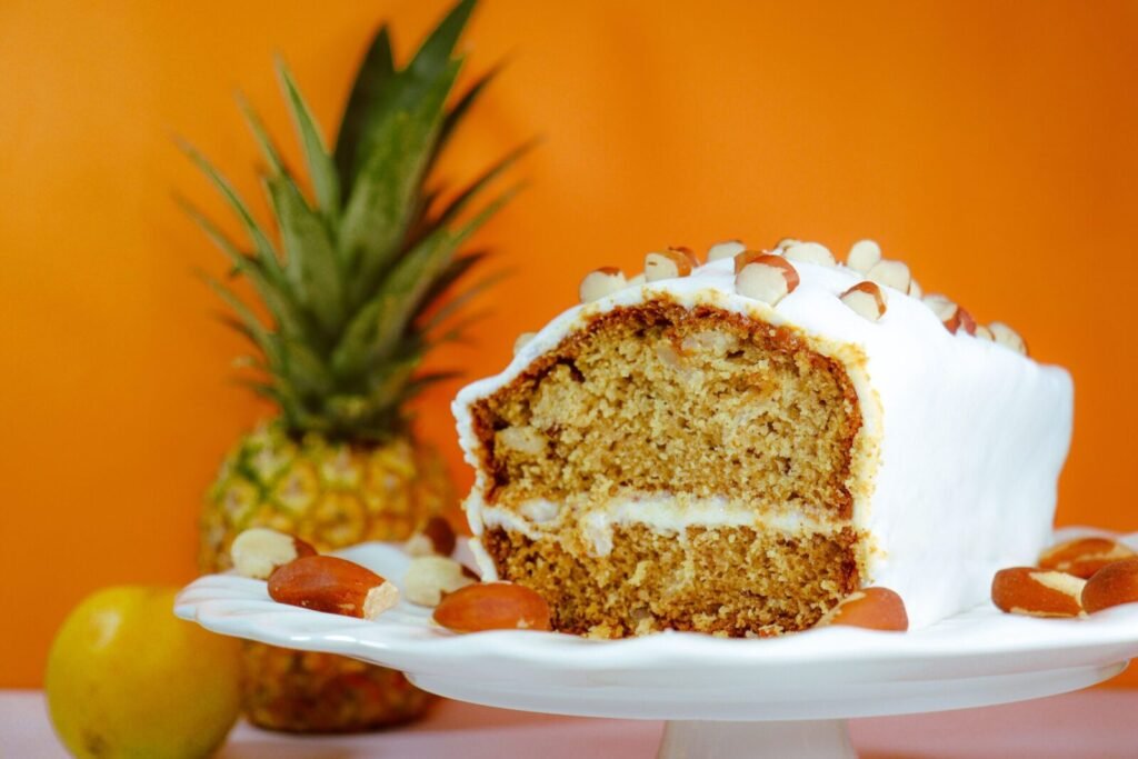 Close-up of a frosted pineapple almond cake on a stand, perfect for dessert lovers.