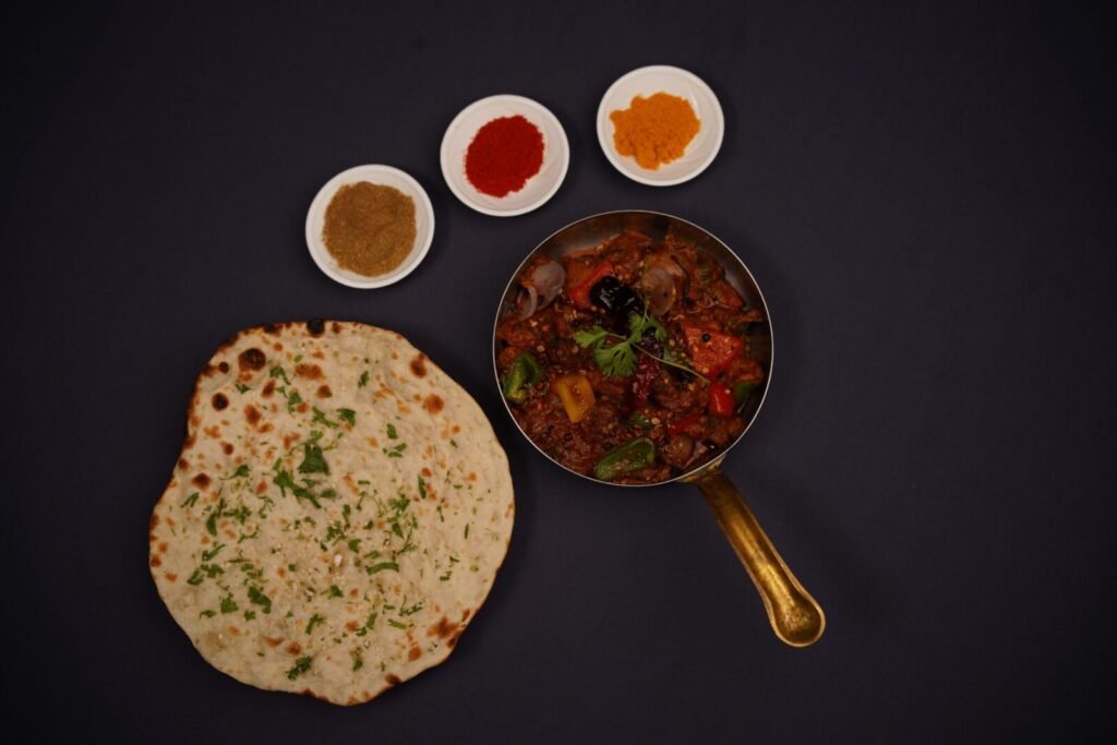 Top view of lachha bread, spices, and Indian curry in a pan. Perfect for food photography.