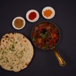 Top view of lachha bread, spices, and Indian curry in a pan. Perfect for food photography.