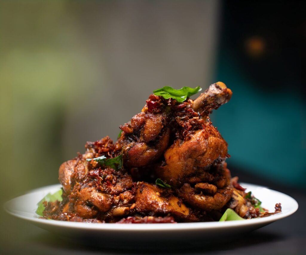 Close-up view of spicy fried chicken drumsticks garnished with herbs, served on a plate.