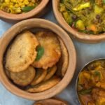 Top view of clay pots with a variety of Indian vegetarian dishes, ideal for food enthusiasts.