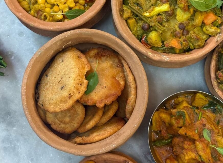 Top view of clay pots with a variety of Indian vegetarian dishes, ideal for food enthusiasts.