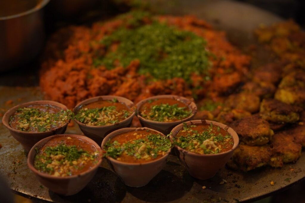 Close-up of Indian street food with vibrant toppings and spices in clay pots.