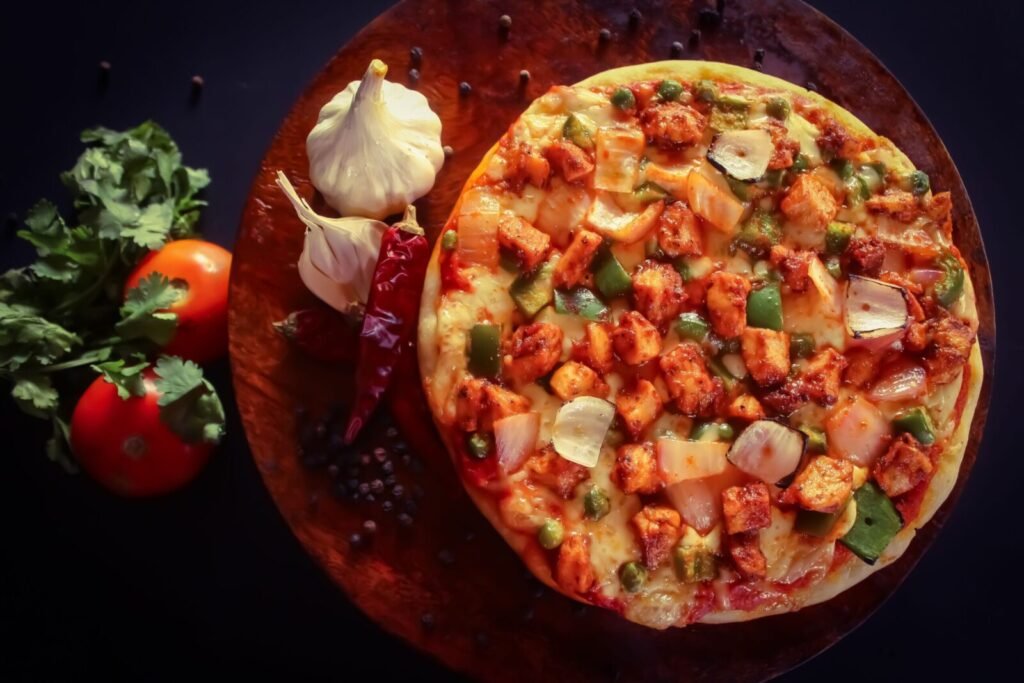 Close-up of homemade pizza topped with vegetables and cheese on a rustic wooden board.