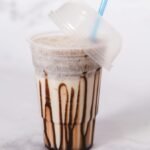 Delicious iced chocolate shake in a clear plastic cup with a straw, perfect for summer cravings.